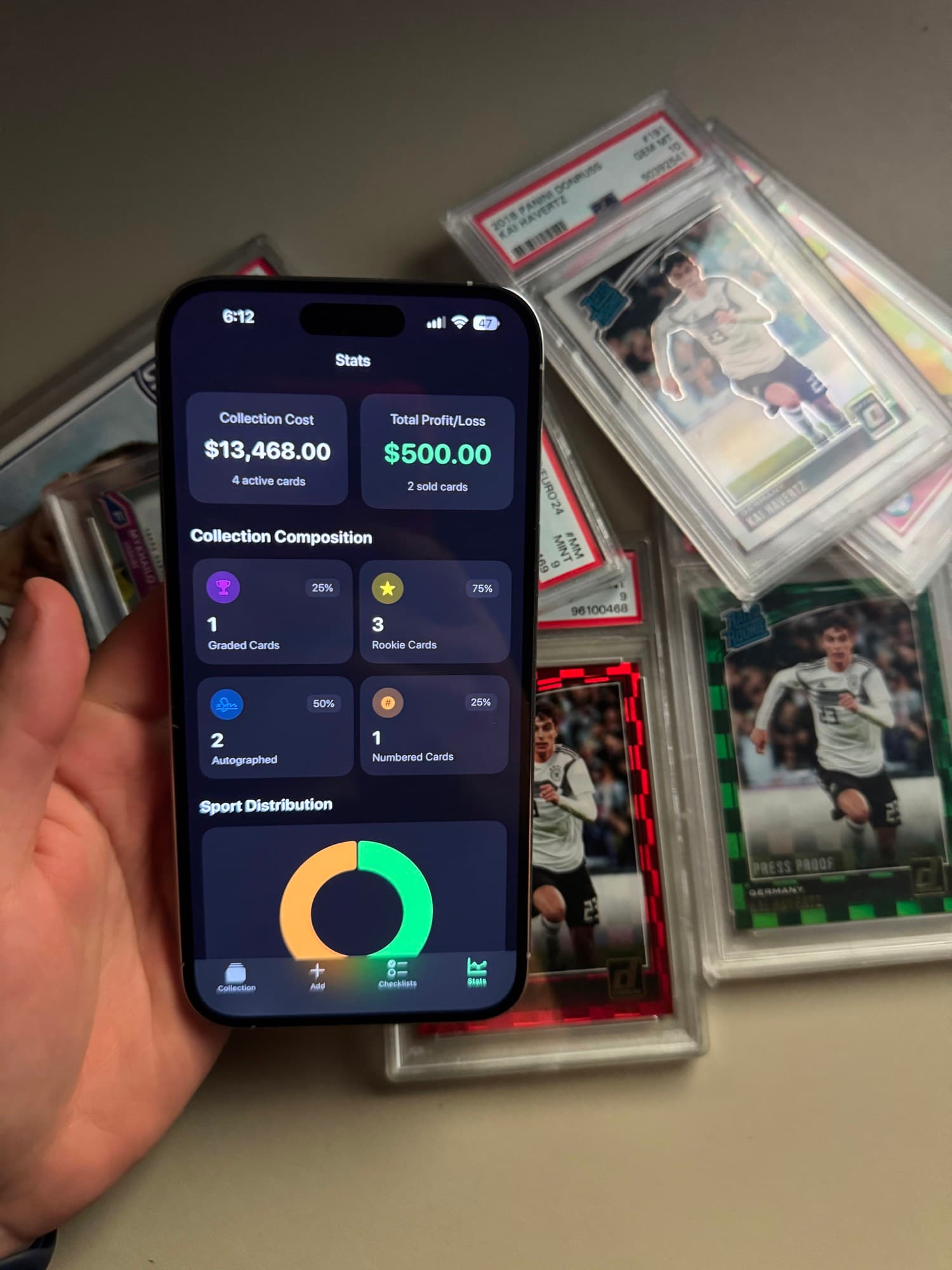 A hand holding an iPhone showing Binder's stats page, with a collection cost of $13,468 and a profit of $500, over a pile of graded cards